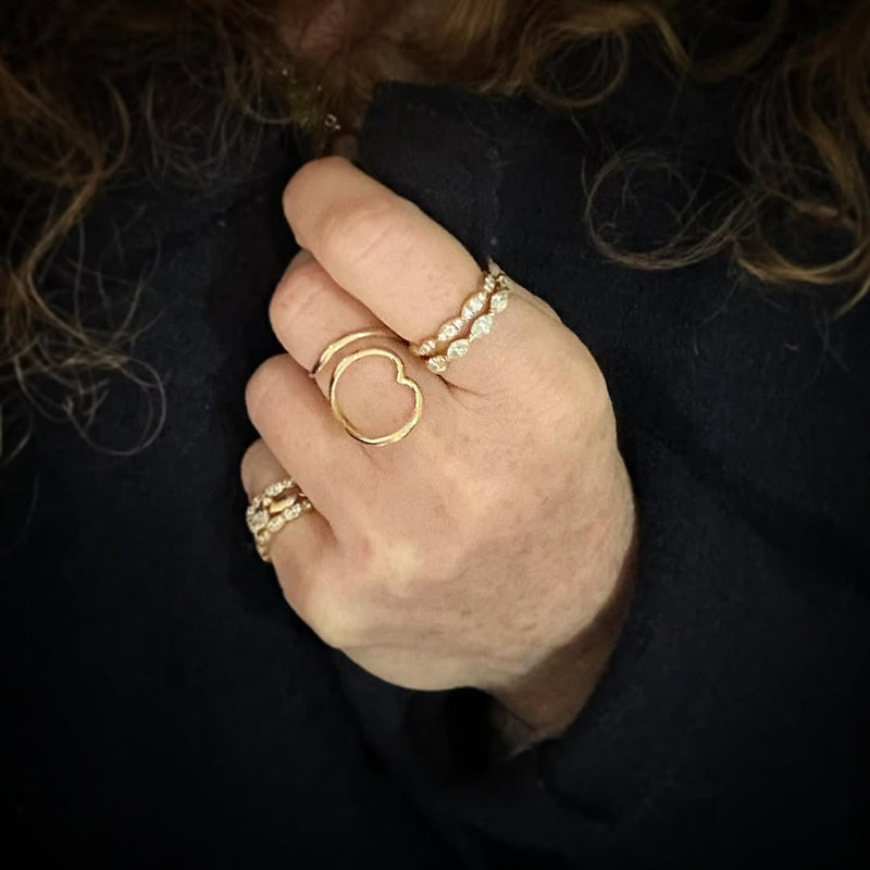 Hand wearing multiple gold rings on a dark background