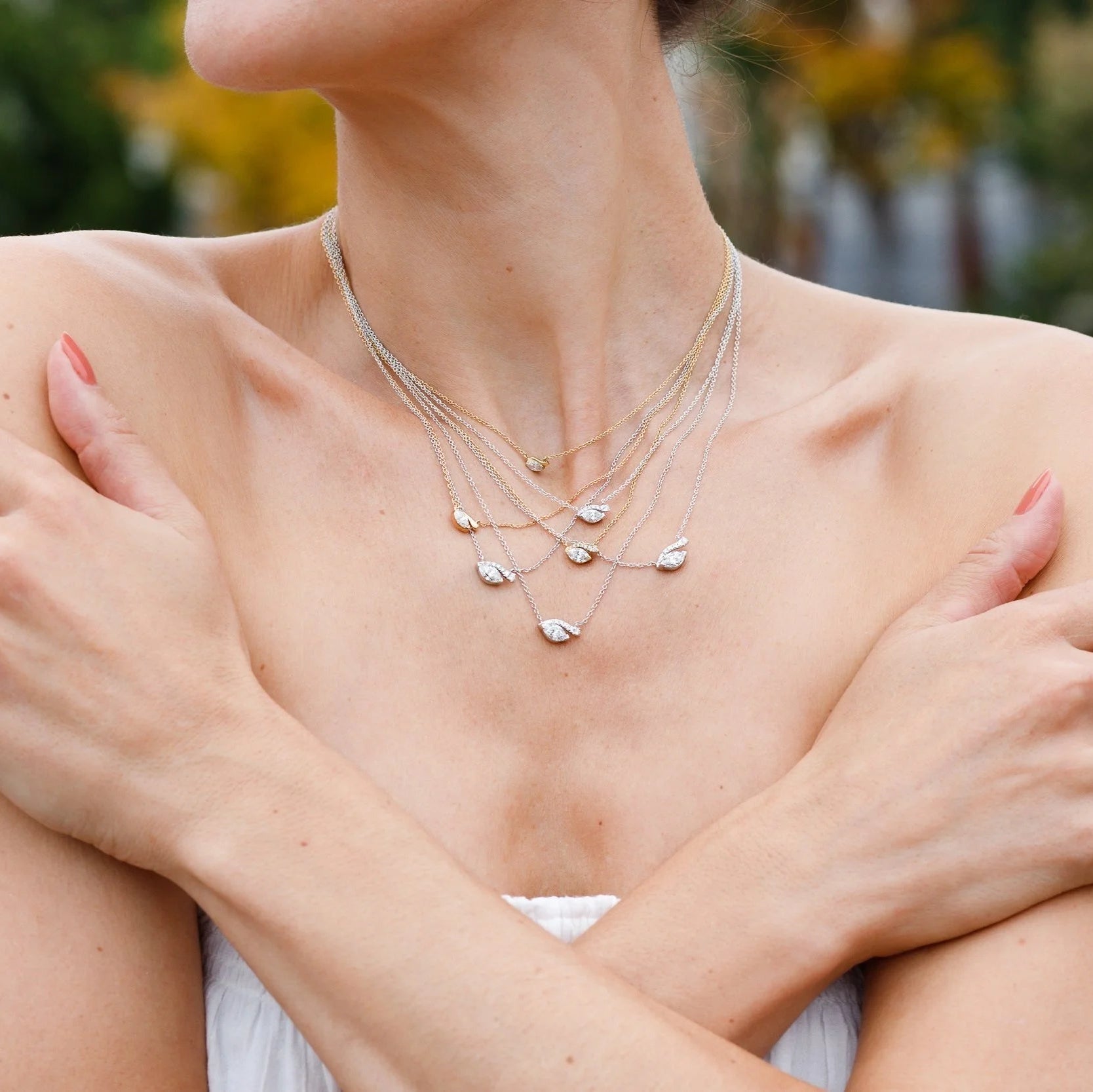 Woman wearing seven look of love diamond necklaces with a blurred outdoor background.