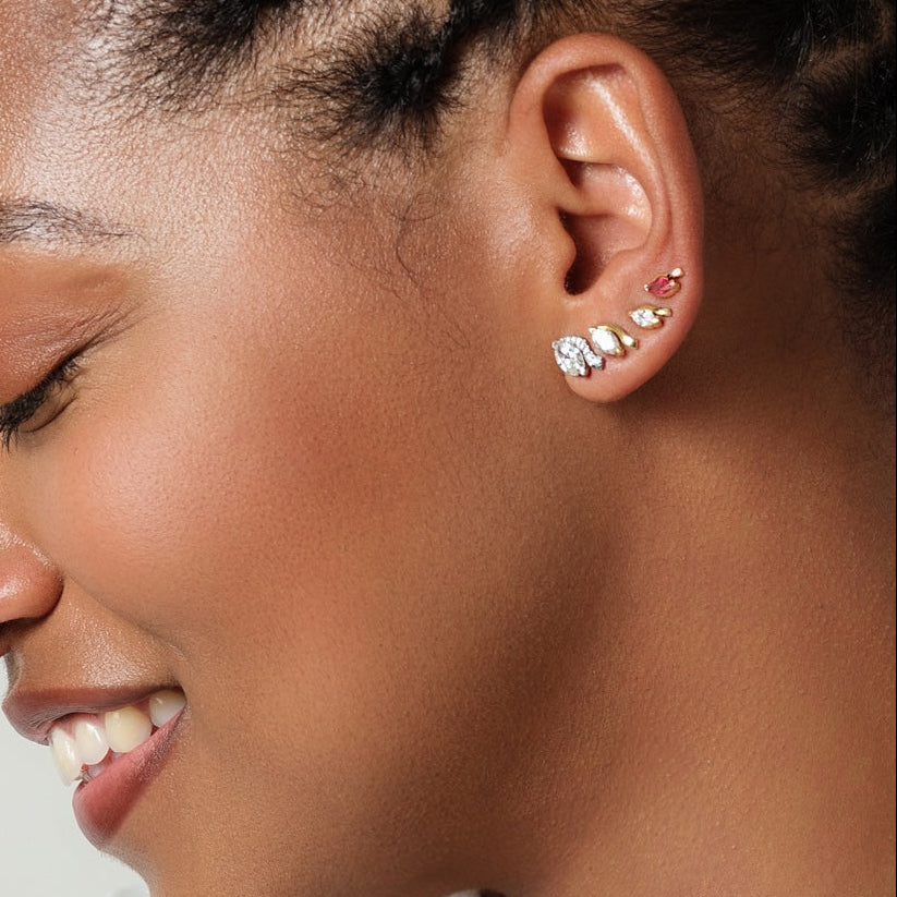 Close-up of a woman's ear wearing multiple earrings with a blurred background
