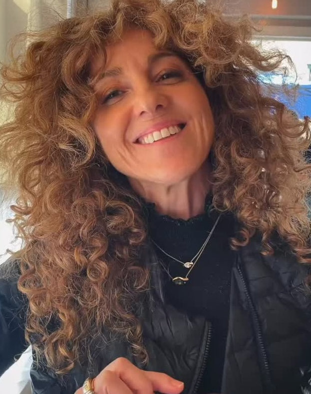 Woman with curly hair wearing a black jacket indoors